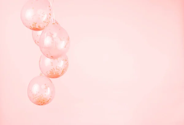 A monochromatic peach pink confetti clear balloons against a light pink backdrop.
