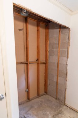 An empty opening where a standing shower bathtub stall was located in a house being after everything was demolished and the house is being renovated.