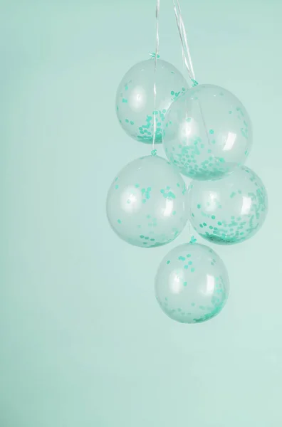 Mint green confetti clear balloons against a light green backdrop.