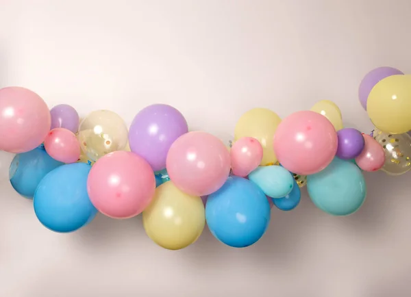 A close up image of a soft pastel balloon garland against a pink background.