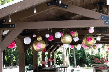 Yerel bir parkta doğum günü partisi için altın ve pembe fenerler asıyorlar..