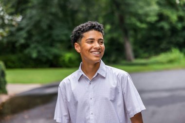 A close up image of a handsome teenage guy laughing and looking away.