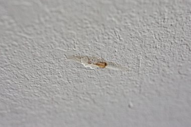 A gash in a textured greige gray beige wall in the interior of a new construction house.