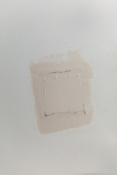 A patch in gray brown greige textured white ceiling of a new construction house.