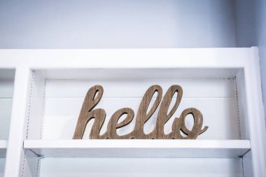 A hellow welcome sign to a house, open house or business sitting on a white shelf.