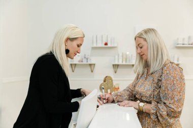 Küçük bir işletme sahibi, bir sağlık merkezindeki müşteri kaydını yaptırıyor..