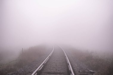 Kalın beyaz sisli tren yolu, arka planda orman. Manzara kavramı. Keder, yalnızlık, çıkmaz. Odaklanmamış