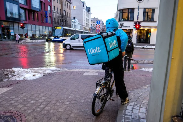 Riga, Latvia - February 9, 2022: Wolt bicycle courier at work in Riga. Food delivery service during pandemic. — Stock Photo, Image
