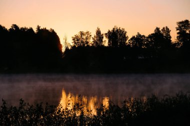 Very beautiful sunrise in summer over a foggy lake. Early morning in summer in nature. Defocused. High quality photo