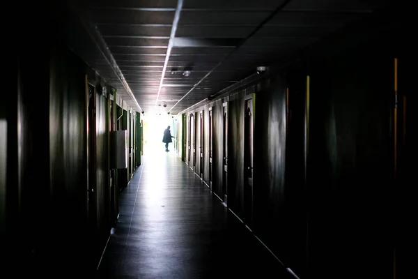 Woman walking alone in the dark. Woman in a dark, long corridor, defocused. High quality photo