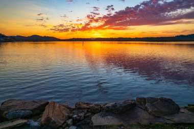 Orta Sahildeki Woy Woy, NSW, Avustralya 'daki Brisbane Suyu' na yansıyan yüksek bulutlu hava gündoğumu manzarası..