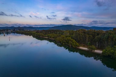 Yağmurdan sonra havadan gün doğumu su manzarası Orta Sahildeki Woy Woy körfezine yansıyan bulutlar, NSW, Avustralya.