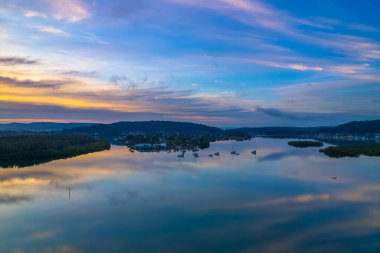 Yağmurdan sonra havadan gün doğumu su manzarası Orta Sahildeki Woy Woy körfezine yansıyan bulutlar, NSW, Avustralya.