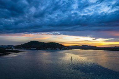 Bulutlar gökyüzünü doldurdu. Gündoğumu su manzarası. Woy Woy 'da Merkez Sahili, NSW, Avustralya..