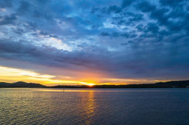 Bulutlar gökyüzünü doldurdu. Gündoğumu su manzarası. Woy Woy 'da Merkez Sahili, NSW, Avustralya..