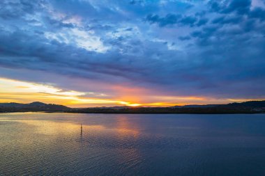 Bulutlar gökyüzünü doldurdu. Gündoğumu su manzarası. Woy Woy 'da Merkez Sahili, NSW, Avustralya..