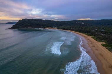 Deniz kıyısında gökyüzü bulutlarla kaplıyken hava gündoğumu Central Coast, NSW, Avustralya 'da Umina Sahili' nde.