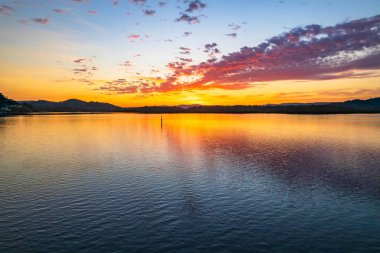 Orta Sahildeki Woy Woy, NSW, Avustralya 'daki Brisbane Suyu' na yansıyan yüksek bulutlu hava gündoğumu manzarası..