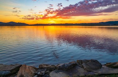 Orta Sahildeki Woy Woy, NSW, Avustralya 'daki Brisbane Suyu' na yansıyan yüksek bulutlu hava gündoğumu manzarası..