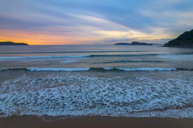 Deniz kıyısında gökyüzü bulutlarla kaplıyken hava gündoğumu Central Coast, NSW, Avustralya 'da Umina Sahili' nde.