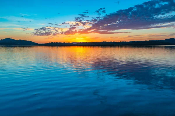 Güneş doğarken yüksek bulutlu su manzarası Orta Sahilde, NSW, Avustralya 'da, Woy Woy' daki Brisbane Suyu 'nu yansıtıyor..