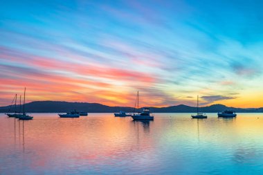 Central Coast, NSW, Avustralya 'daki Koolewong rıhtımında teknelerle renkli bir gün doğumu, yüksek bulut ve yansımalar..