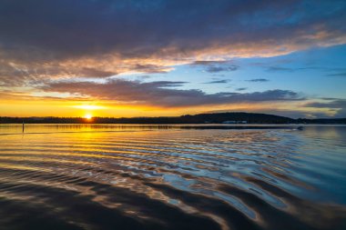 Gündoğumu, bulut ve yansımalar Orta Sahildeki Woy Woy rıhtımında, NSW, Avustralya.