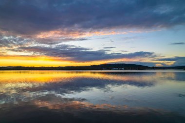 Gündoğumu, bulut ve yansımalar Orta Sahildeki Woy Woy rıhtımında, NSW, Avustralya.