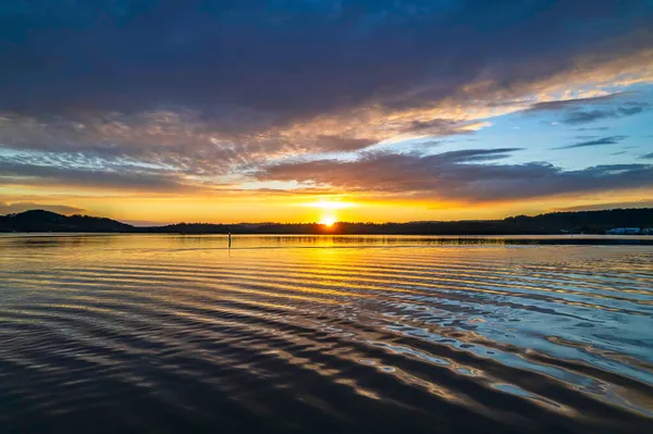 Gündoğumu, bulut ve yansımalar Orta Sahildeki Woy Woy rıhtımında, NSW, Avustralya.