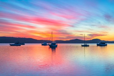 Central Coast, NSW, Avustralya 'daki Koolewong rıhtımında teknelerle renkli bir gün doğumu, yüksek bulut ve yansımalar..