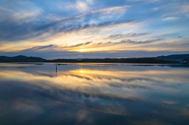 Yağmurdan sonra havadan gün doğumu su manzarası Orta Sahildeki Woy Woy körfezine yansıyan bulutlar, NSW, Avustralya.