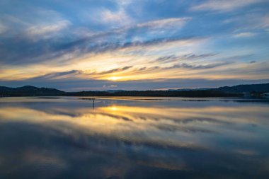 Yağmurdan sonra havadan gün doğumu su manzarası Orta Sahildeki Woy Woy körfezine yansıyan bulutlar, NSW, Avustralya.