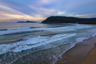 Deniz kıyısında gökyüzü bulutlarla kaplıyken hava gündoğumu Central Coast, NSW, Avustralya 'da Umina Sahili' nde.