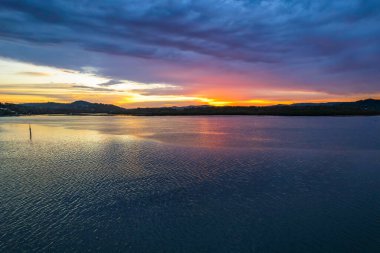Bulutlar gökyüzünü doldurdu. Gündoğumu su manzarası. Woy Woy 'da Merkez Sahili, NSW, Avustralya..