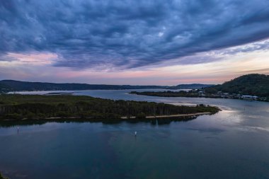 Bulutlar gökyüzünü doldurdu. Gündoğumu su manzarası. Woy Woy 'da Merkez Sahili, NSW, Avustralya..