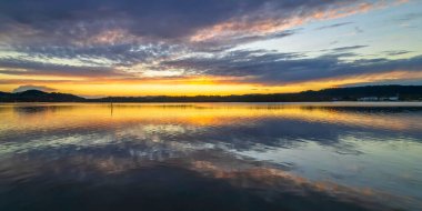 Gündoğumu, bulut ve yansımalar Orta Sahildeki Woy Woy rıhtımında, NSW, Avustralya.
