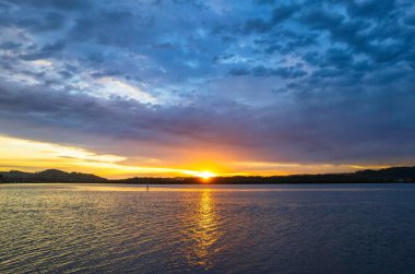 Bulutlar gökyüzünü doldurdu. Gündoğumu su manzarası. Woy Woy 'da Merkez Sahili, NSW, Avustralya..