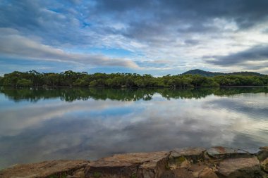 Sabahın erken saatlerinde Woy Woy, NSW, Avustralya 'daki kanalda bulutlar ve yansımalar.