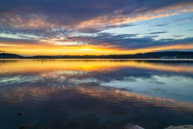 Gündoğumu, bulut ve yansımalar Orta Sahildeki Woy Woy rıhtımında, NSW, Avustralya.