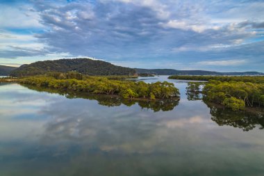 Sabahın erken saatlerinde Woy Woy, NSW, Avustralya 'daki kanalda bulutlar ve yansımalar.