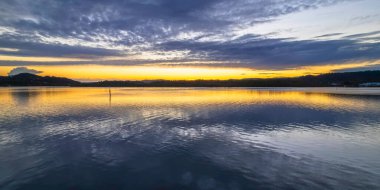 Gündoğumu, bulut ve yansımalar Orta Sahildeki Woy Woy rıhtımında, NSW, Avustralya.