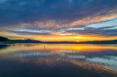 Gündoğumu, bulut ve yansımalar Orta Sahildeki Woy Woy rıhtımında, NSW, Avustralya.