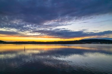 Gündoğumu, bulut ve yansımalar Orta Sahildeki Woy Woy rıhtımında, NSW, Avustralya.