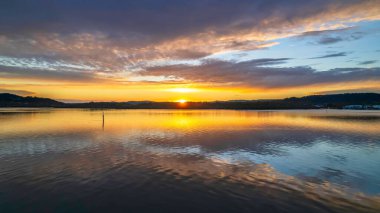 Gündoğumu, bulut ve yansımalar Orta Sahildeki Woy Woy rıhtımında, NSW, Avustralya.