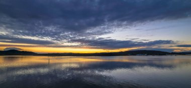 Gündoğumu, bulut ve yansımalar Orta Sahildeki Woy Woy rıhtımında, NSW, Avustralya.