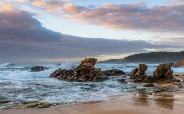 Avustralya, NSW 'nin güney kıyısındaki Eurobadalla Shire' de Bermagui 'de bulutlu ve dalgalı gün doğumu deniz manzarası..