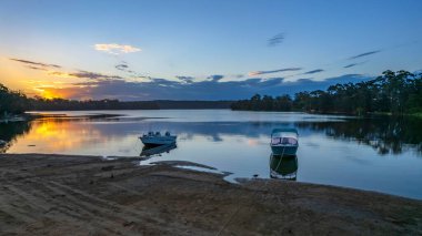 Güneş Wallaga Gölü 'nde batarken, Bermagui Sapphire kıyısında, Avustralya.