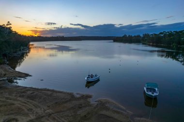 Güneş Wallaga Gölü 'nde batarken, Bermagui Sapphire kıyısında, Avustralya.