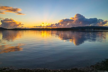 Bulutlar ve yansımalarla birlikte gündoğumu suları Central Coast, NSW, Avustralya 'daki Woy Woy rıhtımında..