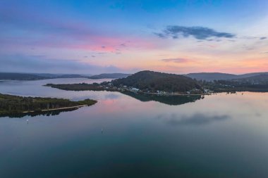 Gündoğumu, bulutlar ve yansımalar Orta Sahildeki Woy Woy Rıhtımı 'nda, NSW, Avustralya.